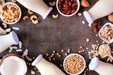 Süt içermeyen vejetaryen bitki. Süt şişelerinde çeşitli malzemeler var. Fotokopi alanı olan kahverengi bir arkaplan üzerinde görünüm.