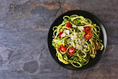 Domates ve fesleğen soslu kabaklı makarna. Koyu bir arkaplanda üst görünüm. Sağlıklı beslenme, düşük karbonhidrat diyeti.