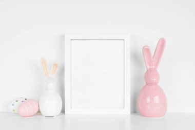Paskalya yumurtaları ve beyaz bir rafta modern cam tavşan dekoru olan beyaz bir portre yap. Boşluğu kopyala.