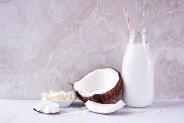 İçinde malzemeler olan eski bir şişede hindistan cevizi sütü. Vejetaryen, bitki bazlı, sütsüz. Parlak bir arkaplan karşısında yan görünüm.