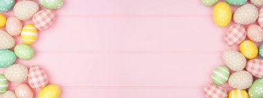 Paskalya çifte sınırı. Pembe ahşap kaplama arka planda pastel renkli yumurtalar. Kopyalama alanı ile genel görünüm.