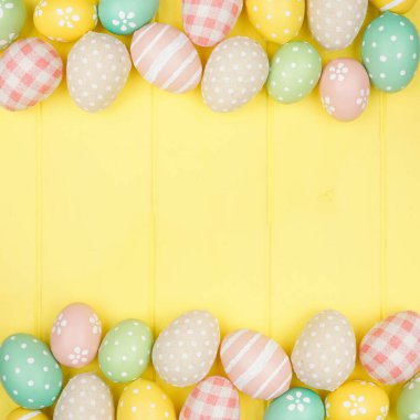 Paskalya çifte sınırı modern çiftlik evi kumaşı ve pastel yumurtalarla kare sarı ahşap arka plan üzerinde. Kopyalama alanı ile görünümün üstünde.