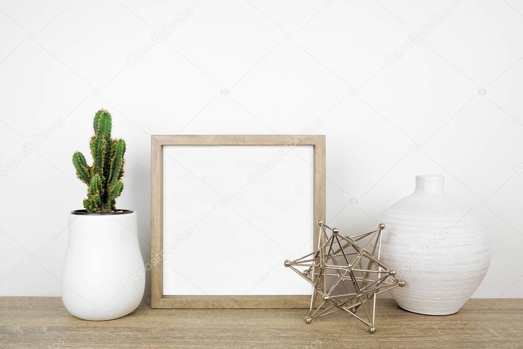 Mock up square wood frame with modern home decor. Wood shelf against a white wall.  Cactus plant vases and geometric table top decoration. Copy space.