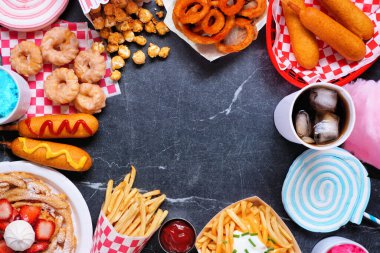 Karnaval temalı yemek çerçevesi koyu bir arka planda. Fotokopi alanı ile görüntünün üstünde. Yaz festivali konsepti. Sosisli sandviç, huni keki, pamuk şeker ve atıştırmalıklar..