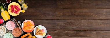 Serin yaz ziyafetleri köşedeki sınır. Dondurma, buzlu şeker ve meyve çeşitleri. Koyu ahşap bir arkaplan üzerine genel manzara.