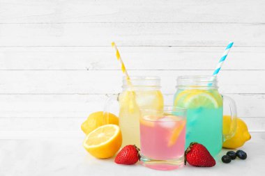 Renkli yaz limonataları. Beyaz ahşap arka planda meyve içerikli bir kümede üç renk.