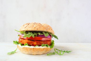 Sağlıklı, bitkisel etsiz nohut burgeri ve tatlı patates. Beyaz mermer bir arkaplan karşısında yan görünüm.