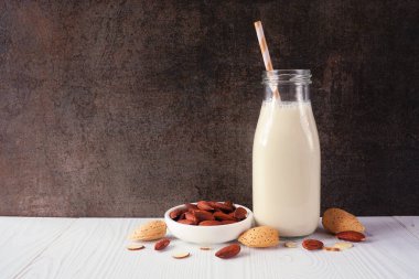 İçinde malzemeler olan badem sütü. Vejetaryen, bitki bazlı, sütsüz. Koyu bir arkaplan karşısında yan görünüm.