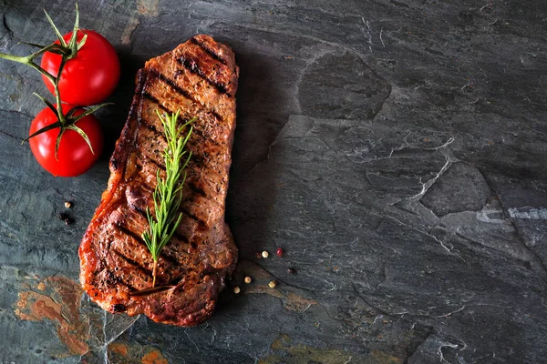 Delicious grilled steak. Above view on a dark slate background with copy space.
