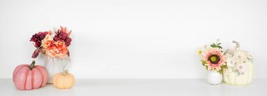 Dekoru beyaz bir rafa, beyaz bir duvar pankartına doğru düşür. Pembe renkte balkabakları ve çiçekler sonbahar renkleri. Boşluğu kopyala.