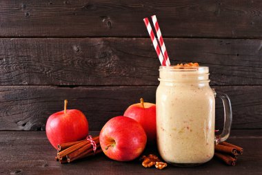 Ceviz ve tarçınlı mason kavanozunda elmalı turtalı smoothie. Koyu bir ahşap arka planda yan manzara.