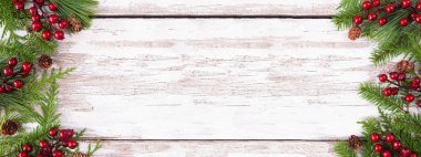 Her zaman yeşil dalları, kırmızı böğürtlenleri ve çam kozalakları olan kışın çifte sınırı. Fotokopi alanı olan kırsal beyaz ahşap afiş arkaplanındaki genel görünüm.