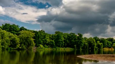 Güneşli bir yaz gününde, huzurlu gölün kıyılarında yeşil ağaçlar büyüyor..