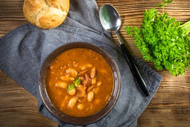 Domates soslu fasulye, pastırma ve siyah kasede sosis. Seçici odak.