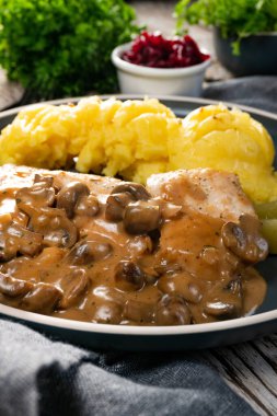 Mantar soslu ızgara tavuk göğsü, patates püresi ve salatalık turşusu ile servis edilir..