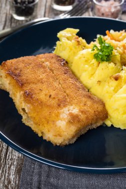 Haşlanmış patates ve sebze salatasıyla servis edilen kızarmış morina filetosu..