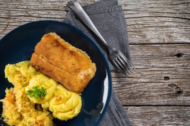 Haşlanmış patates ve sebze salatasıyla servis edilen kızarmış morina filetosu..