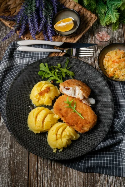 Haşlanmış patates ve sebze salatasıyla servis edilen kızarmış morina filetosu..