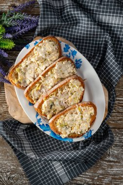 Tahta bir masada uskumru, yumurta ve salatalıklı sandviçler..