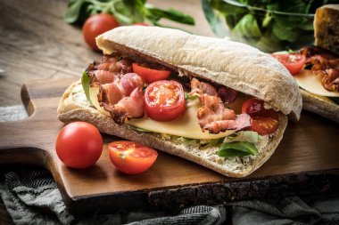 Ahşap tahta üzerinde Roka Salatası, pastırma ve sarı peynirli ciabatta sandviç.