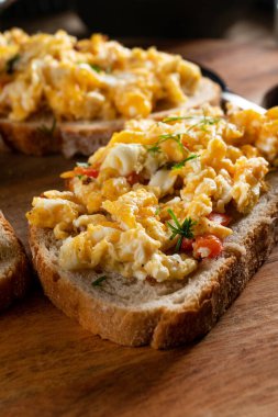 Bir dilim ekmeğin üzerinde çırpılmış yumurta, kırmızı biber, bitki ve domatesle kızartılmış..