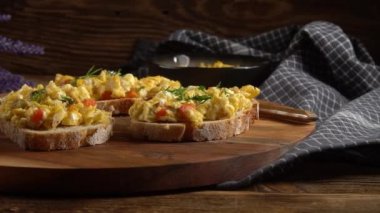 Bir dilim ekmeğin üzerinde çırpılmış yumurta, kırmızı biber, bitki ve domatesle kızartılmış..