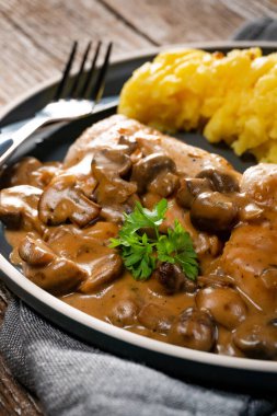 Mantar soslu ızgara tavuk göğsü, patates püresi ve salatalık turşusu ile servis edilir..