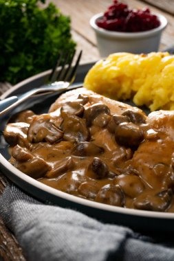 Mantar soslu ızgara tavuk göğsü, patates püresi ve salatalık turşusu ile servis edilir..