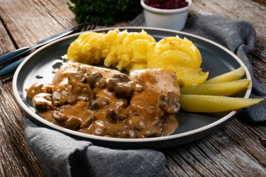 Mantar soslu ızgara tavuk göğsü, patates püresi ve salatalık turşusu ile servis edilir..