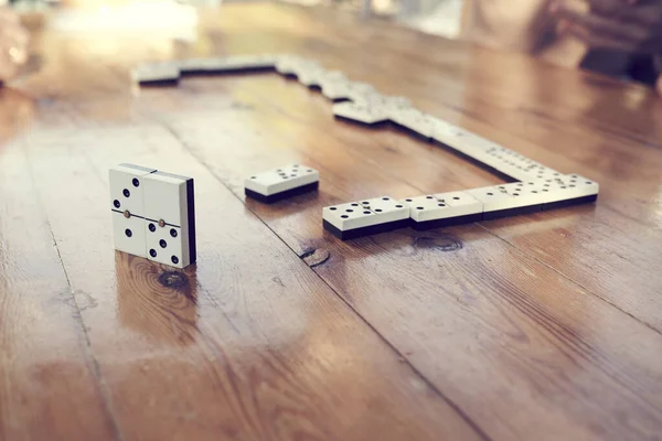 A family playing domino game in a wooden table.