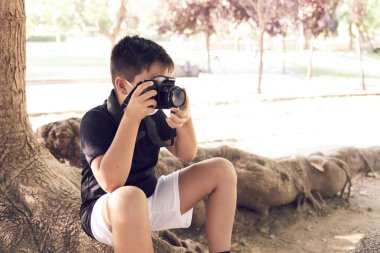 Yeşil gözlü, maske takan küçük şirin bir çocuk elinde bir kamera tutuyor ve fotoğraf çekiyor. Mutlu çocuk fotoğrafçı olmayı hayal ediyor..