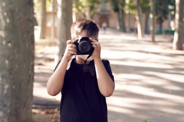 Yeşil gözlü, maske takan küçük şirin bir çocuk elinde bir kamera tutuyor ve fotoğraf çekiyor. Mutlu çocuk fotoğrafçı olmayı hayal ediyor..