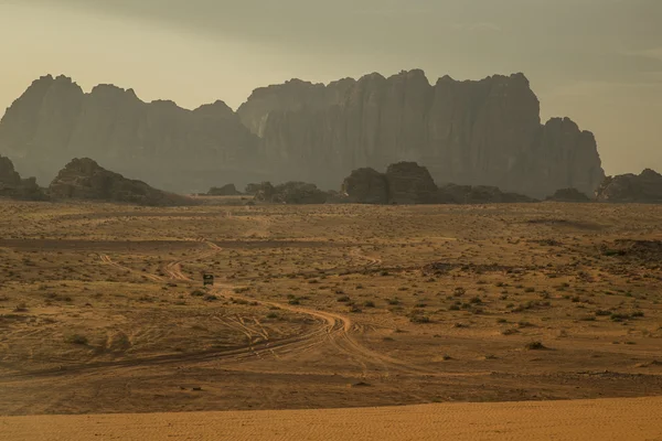 Montanhas no deserto de Wadi Rum com estrada deserta e pequeno carro — Fotografia de Stock