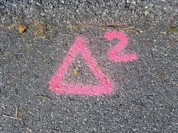 Růžový nebo červený trojúhelník s číslem 2 natřeným na asfaltu — Stock fotografie