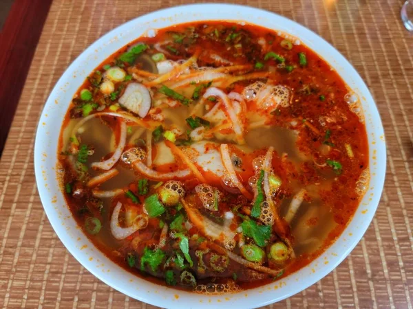 Sopa de carne vietnamita picante en un tazón sobre una mesa — Foto de Stock