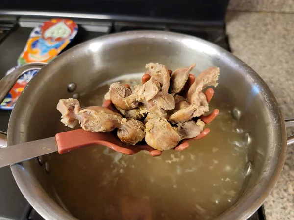 A spoon full of chicken gizzards and pot of water — Stock Photo, Image