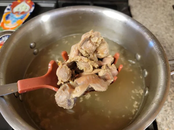 Uma colher cheia de moela de frango e panela de água — Fotografia de Stock