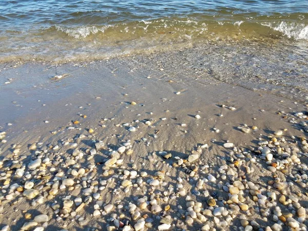 Waves of water with sand on shore of ocean with rocks — Stock Photo, Image