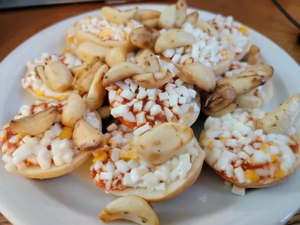 Piccoli bagel di pizza con pezzi di aglio in cima — Foto Stock