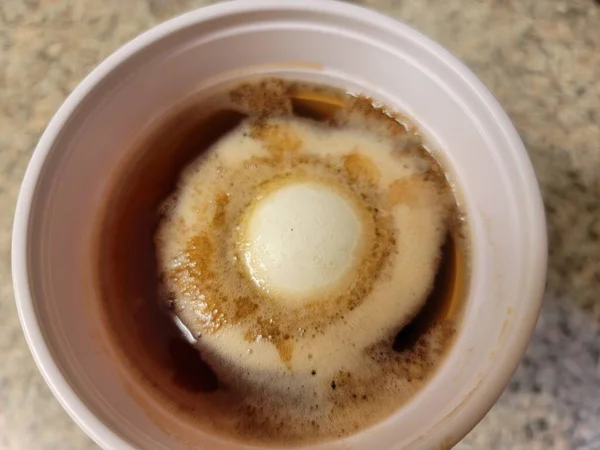 鸡蛋和外壳溶解在柜台上的塑料杯醋中 — 图库照片