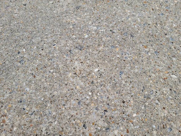 Pebbles and rocks conglomerate in the grey cement on the ground