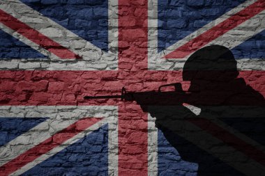 Büyük Britanya bayrağı taşıyan eski tuğla duvardaki asker silueti. Askeri güç.