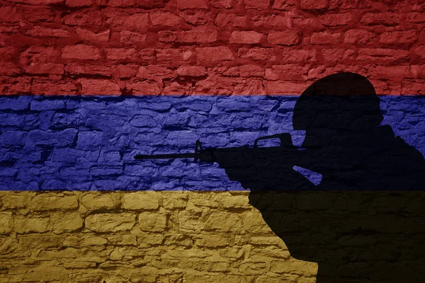 Soldier silhouette on the old brick wall with flag of armenia country. Military strength