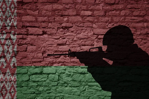 Soldier silhouette on the old brick wall with flag of belarus country. Military strength