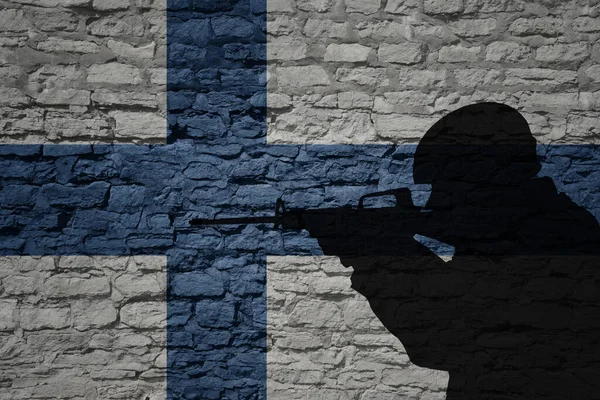 Soldier silhouette on the old brick wall with flag of finland country. Military strength