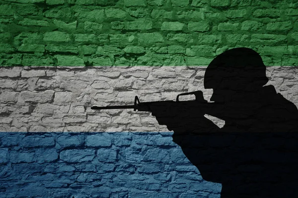 Soldier silhouette on the old brick wall with flag of sierra leone country. Military strength