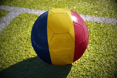 Beyaz satırı yakınlarında yeşil sahada futbol topu Çad bayrağı ile yatıyor