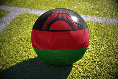 Beyaz satırı yakınlarında yeşil sahada futbol topu Malawi ulusal bayrak ile yatıyor