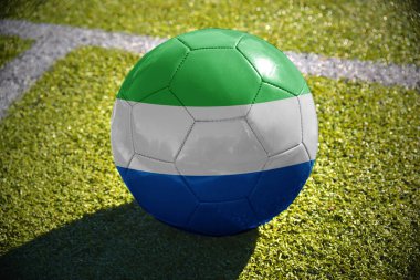 Beyaz satırı yakınlarında yeşil sahada futbol topu sierra leone bayrağı ile yatıyor