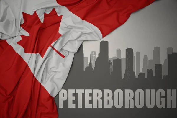 灰色の背景にカナダのカラフルな国旗を振って近くにテキストピーターバラと街の抽象的なシルエット — ストック写真